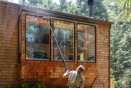 Cloute employee washing windows exterior