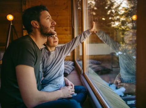 Father and son staring out of clean washed windows